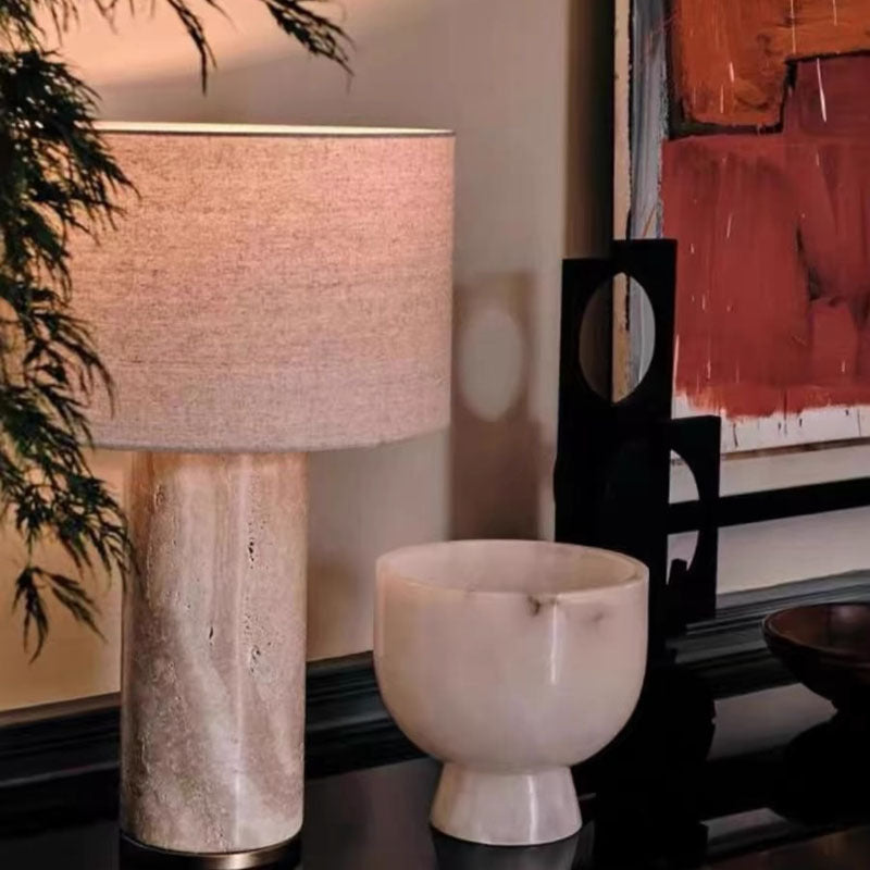 Travertine and linen table lamp glowing warmly in modern interior