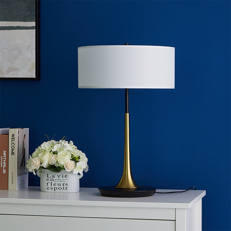 Small black and brass table lamp styled against deep blue wall