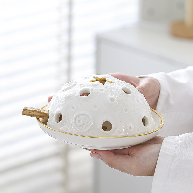 White covered ceramic Palo Santo burner held in hands with gold rim tray