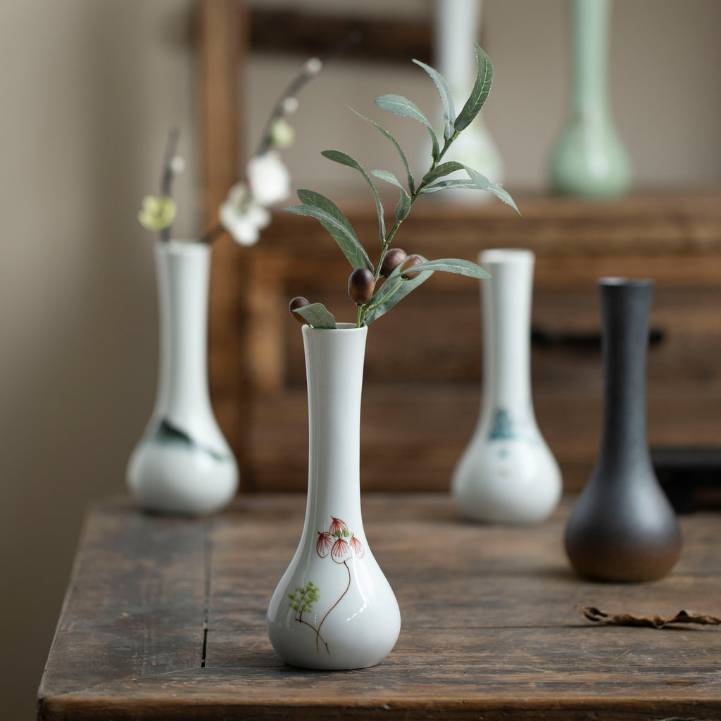 Long-neck ceramic bud vase styled with a single green branch