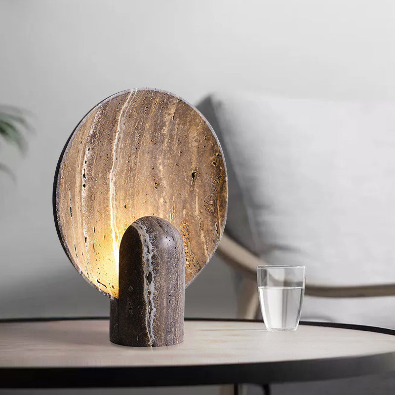 Brown travertine eclipse table lamp styled beside a bed