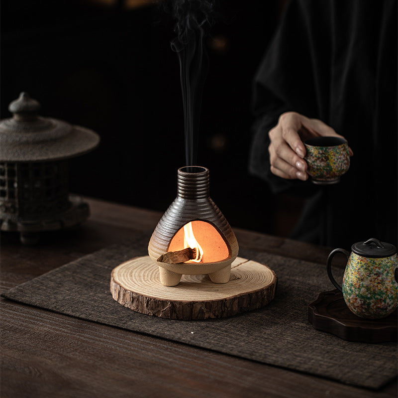 Charcoal ribbed ceramic sacred wood burner glowing on tea table
