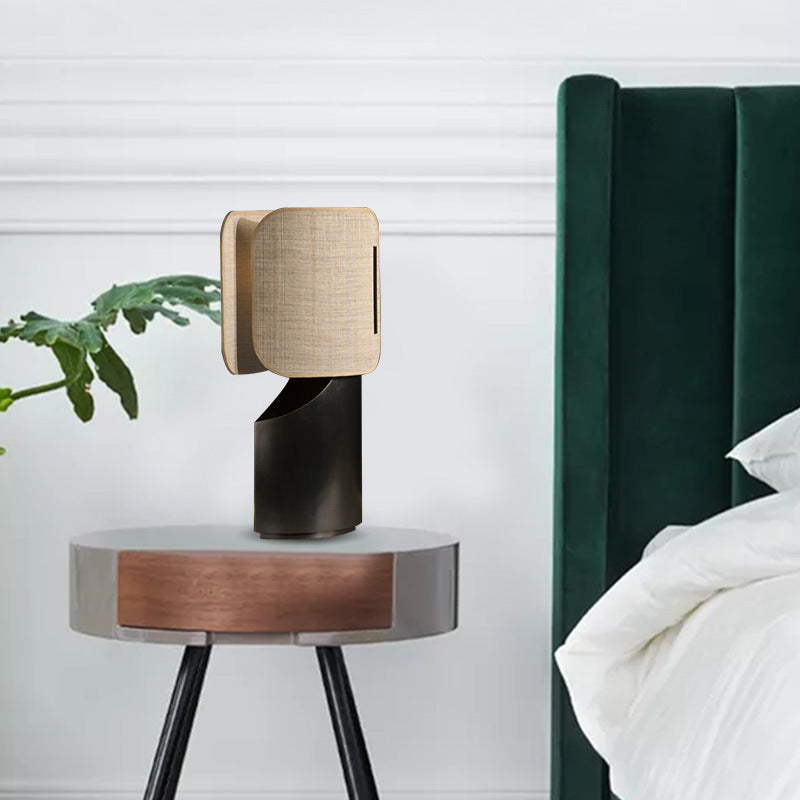 Sculptural black metal table lamp with double layer warm fabric shade in modern bedroom
