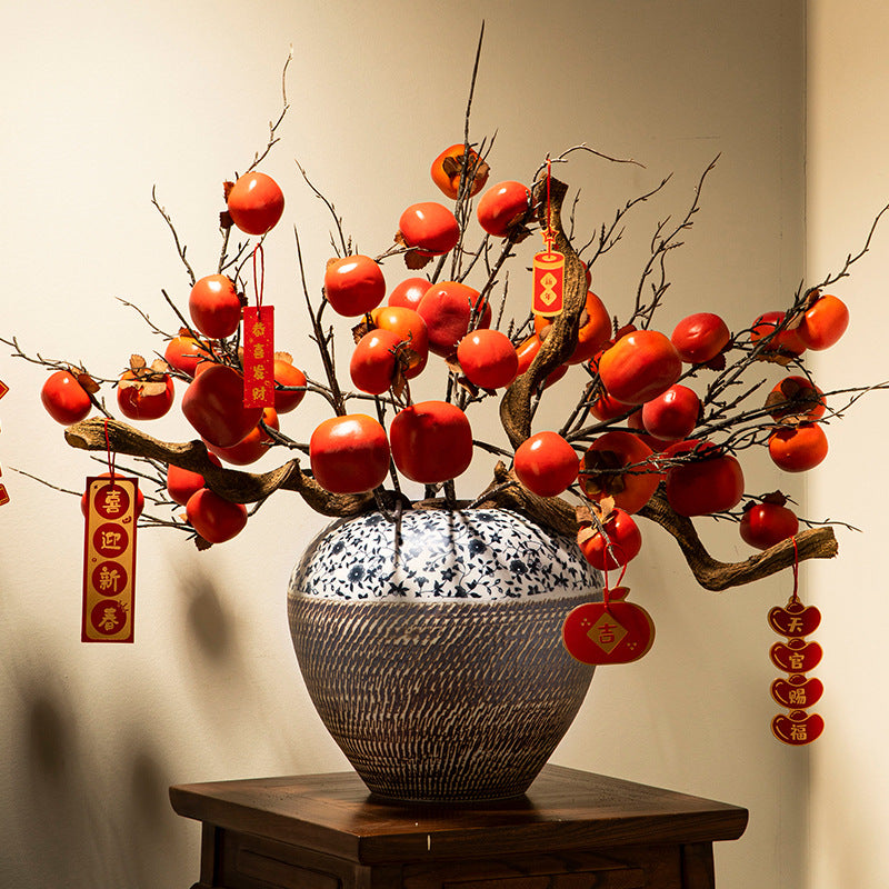 Blue floral ceramic jar styled with red fruit branches and festive ornaments