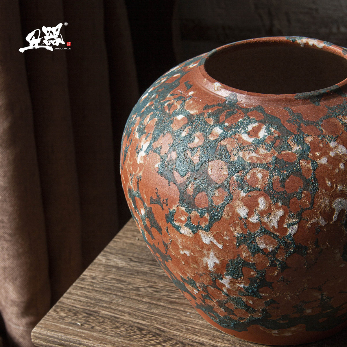 Close-up of terracotta orange and blue-green patina ceramic vase surface