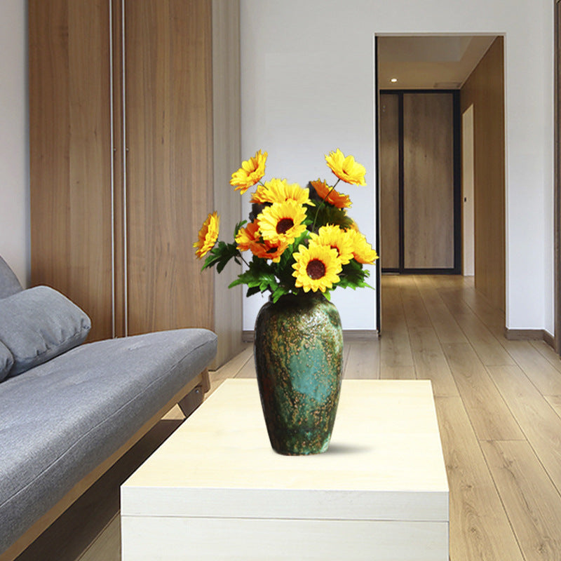 Green patina ceramic vase styled with yellow flowers in modern living room