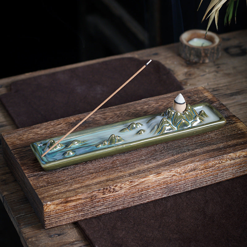 Mountain landscape ceramic incense tray with burning incense stick on wood table