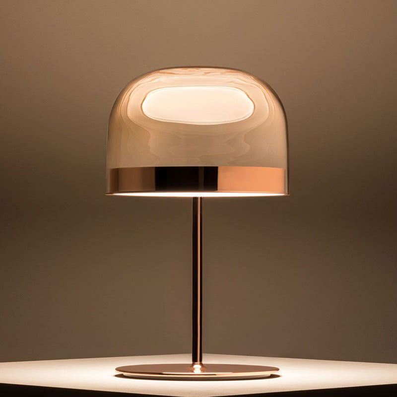 Rose gold glass halo table lamp glowing warmly on table