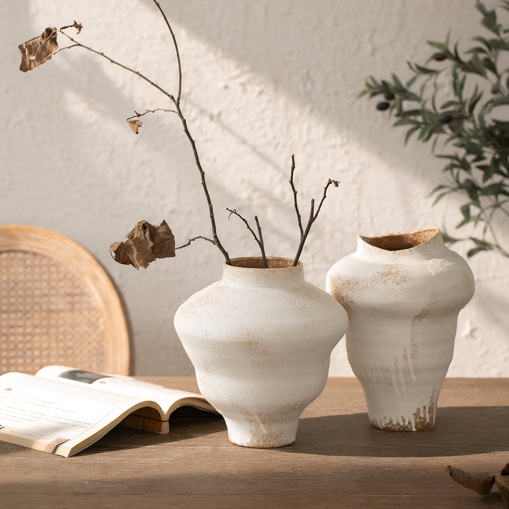 Two asymmetrical white ceramic vases with bare branches