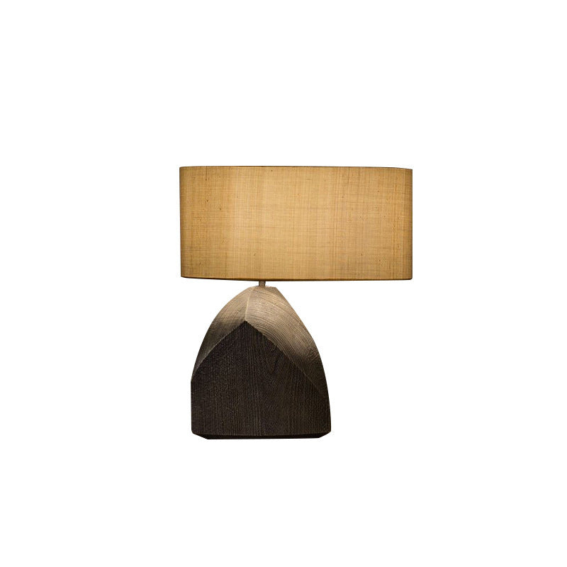 Sculptural table lamp with dark faceted base and warm fabric shade