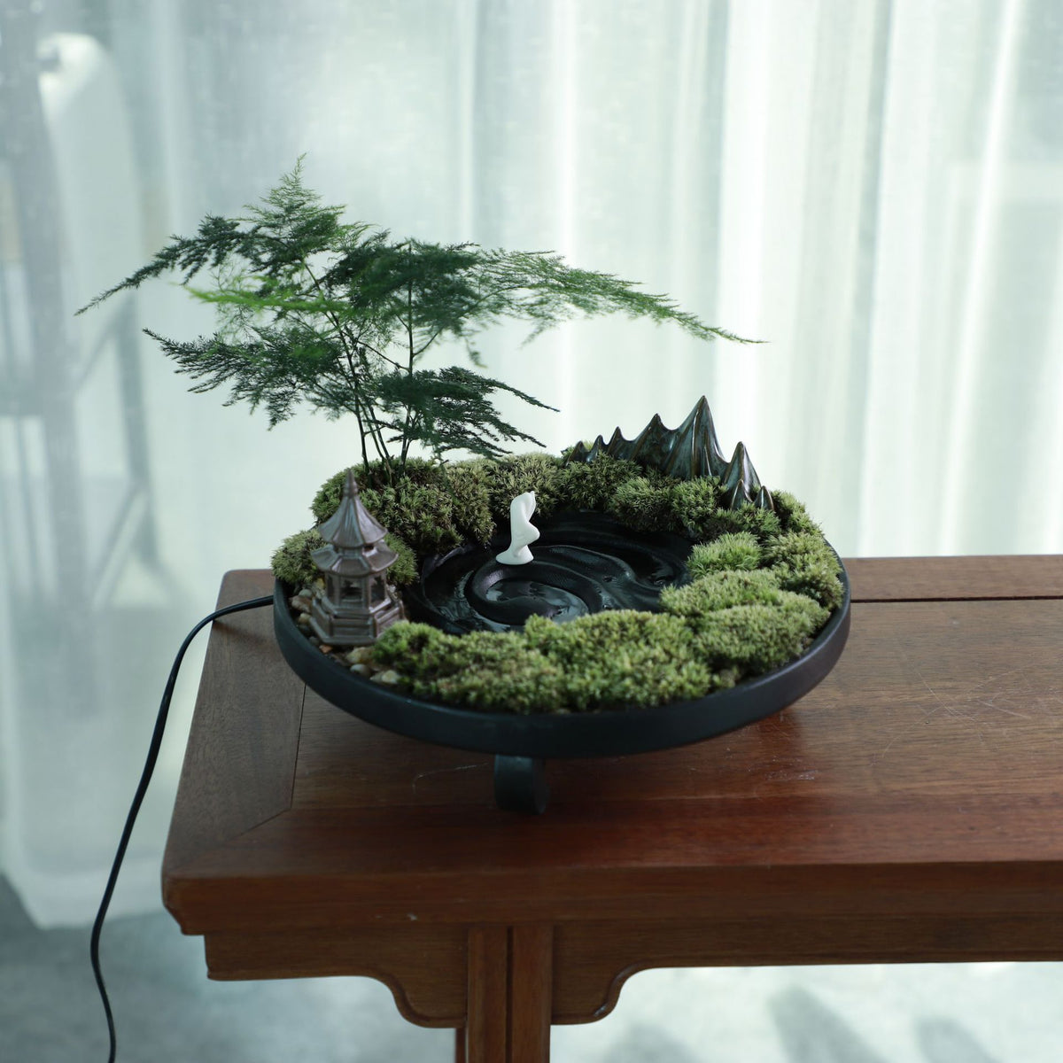 Round black stone Zen micro landscape with ornamental tree moss miniature pagoda and scholar figure