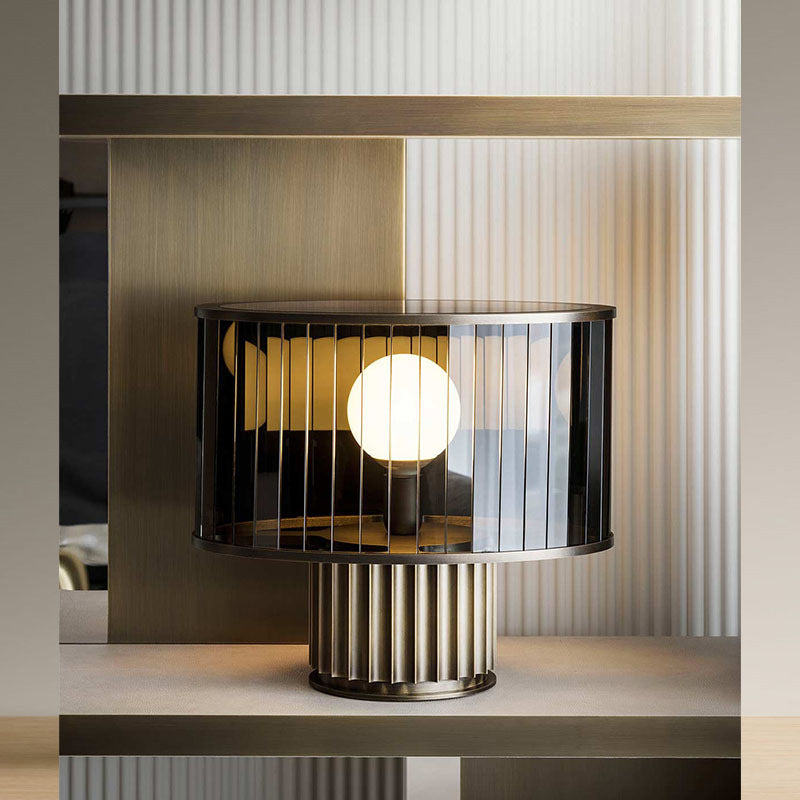 Smoke grey glass cage lamp styled on console with warm globe light