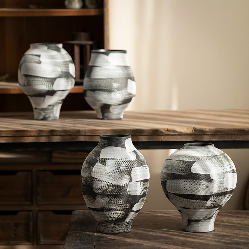 Four black and white graphic ceramic vases arranged on rustic furniture