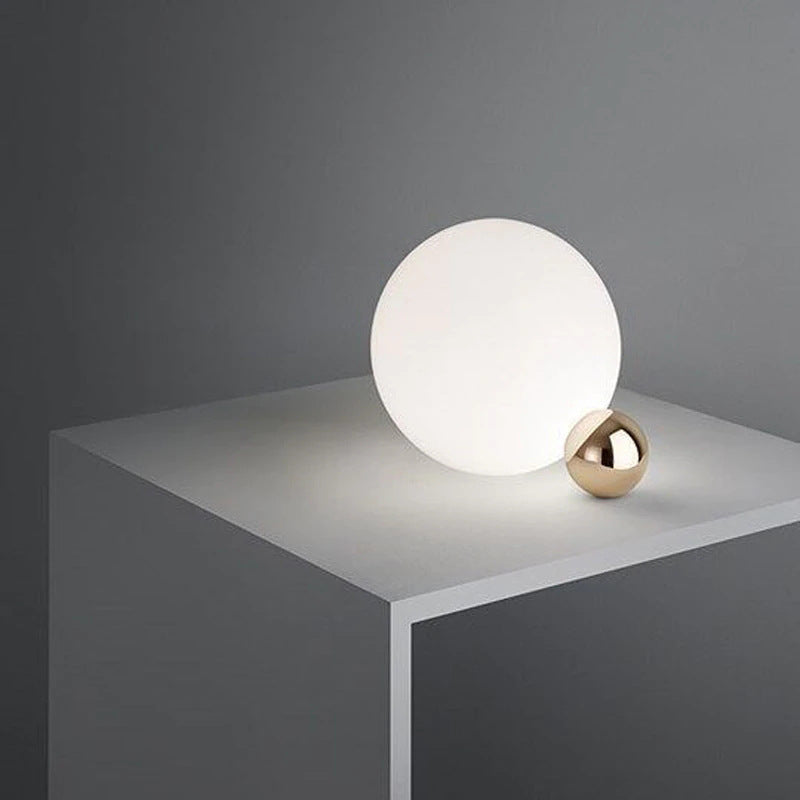 Minimal opal globe and brass sphere bedside table lamp on grey pedestal