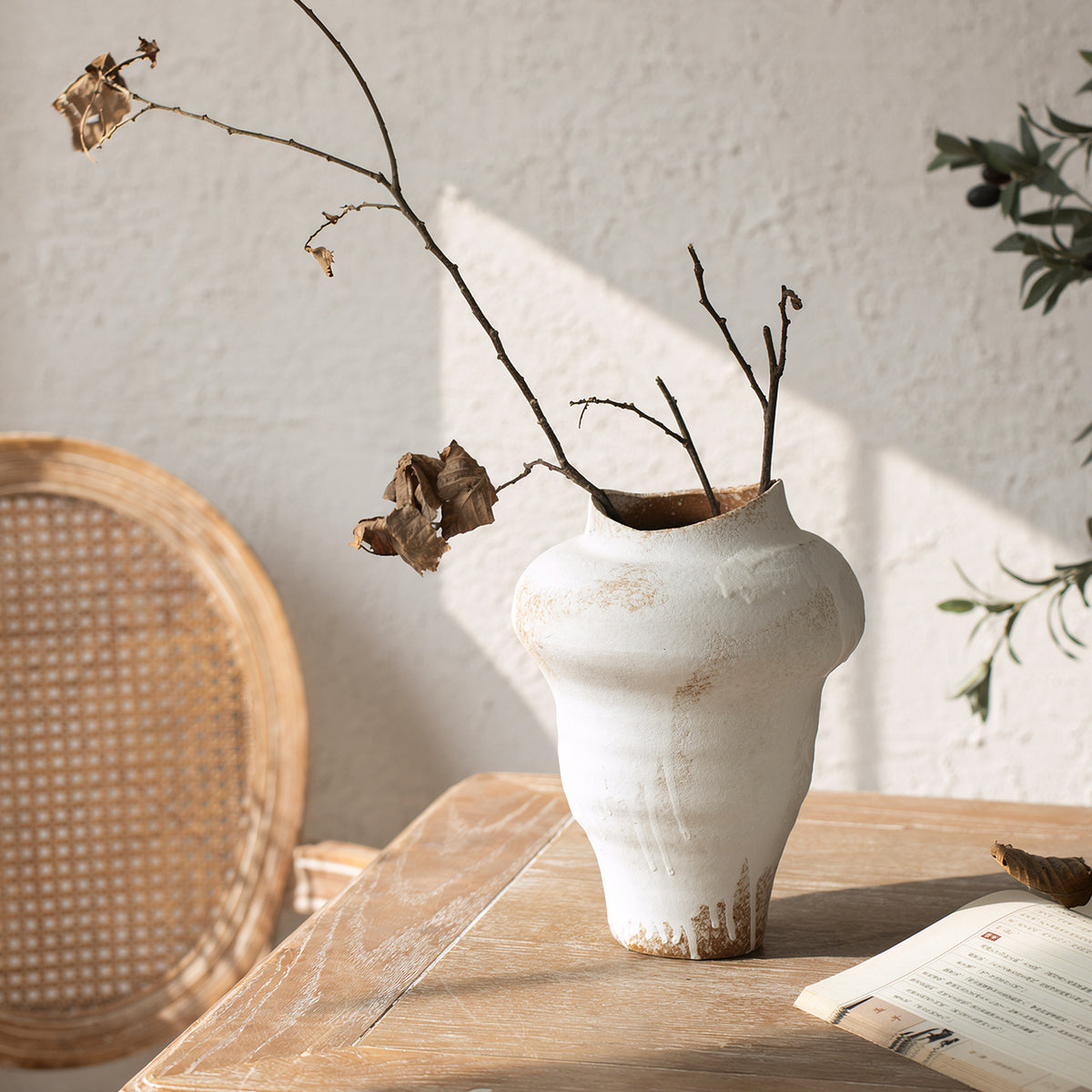 Tall aged white asymmetrical ceramic vase with branch arrangement