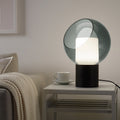 Smoked glass orb table lamp with luminous inner cube and black marble base in bedroom