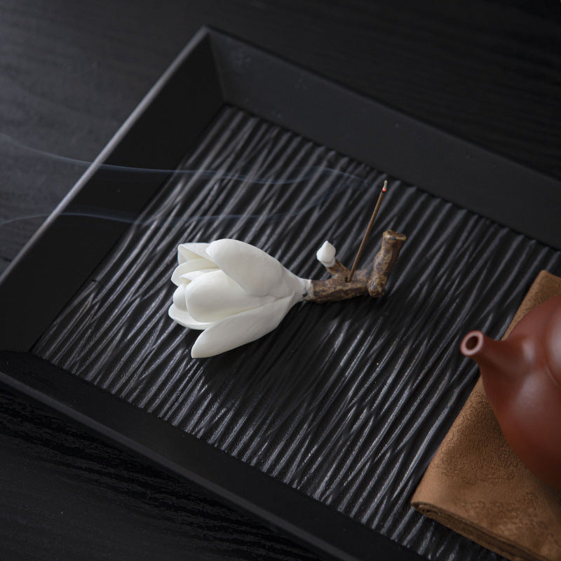 White magnolia ceramic incense holder styled on a black tea tray