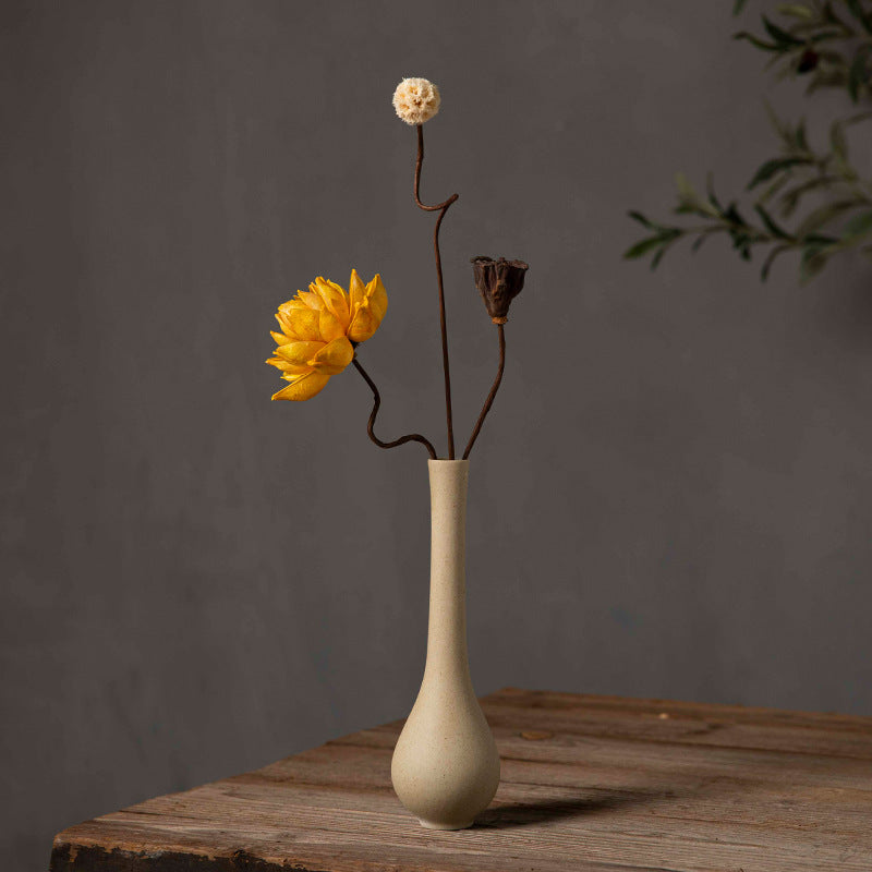 Tall slender beige coarse-clay bud vase with yellow flower