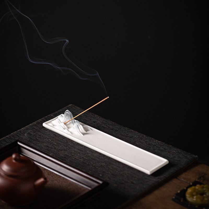 Ivory white ceramic mountain incense stick tray styled on dark tea table