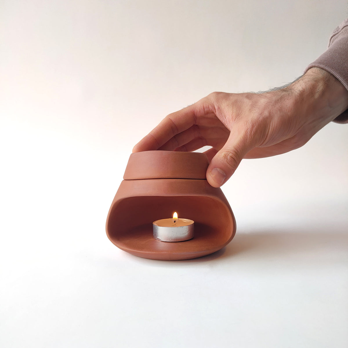 Terracotta ceramic oil burner with removable top aroma bowl being lifted