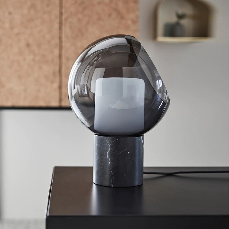 Smoked glass orb table lamp with luminous cube on dark marble base