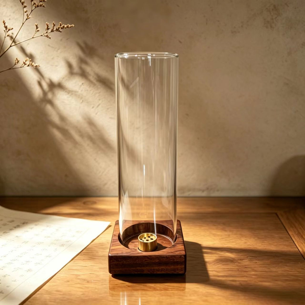 Wind-shield glass incense burner with warm wood base on sunlit desk