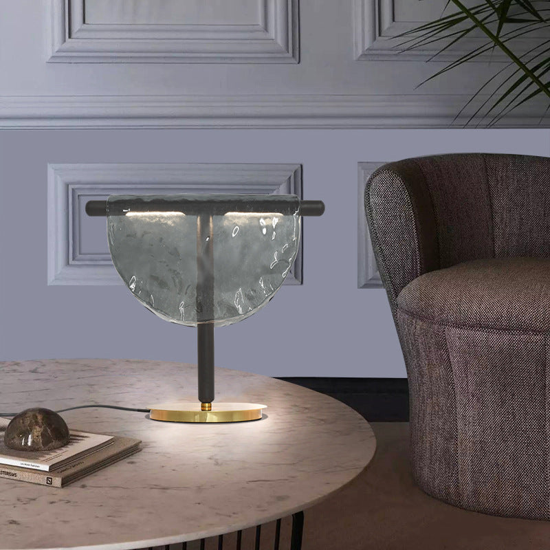 Amber half moon artisan glass table lamp with slim black metal frame and brass base