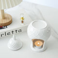 White ceramic oil burner styled with perfume bottle and flowers