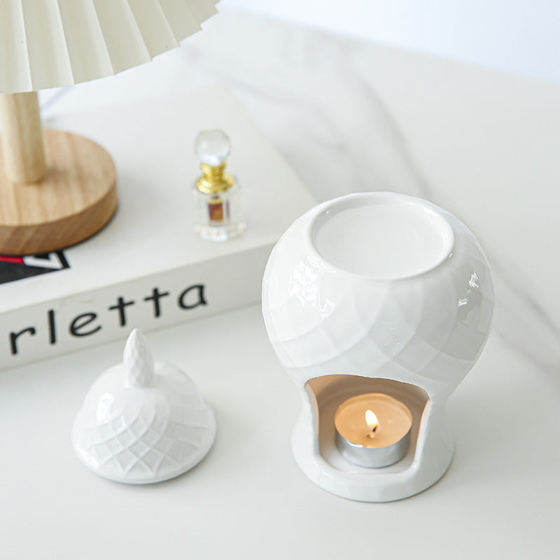 White ceramic oil burner styled with perfume bottle and flowers