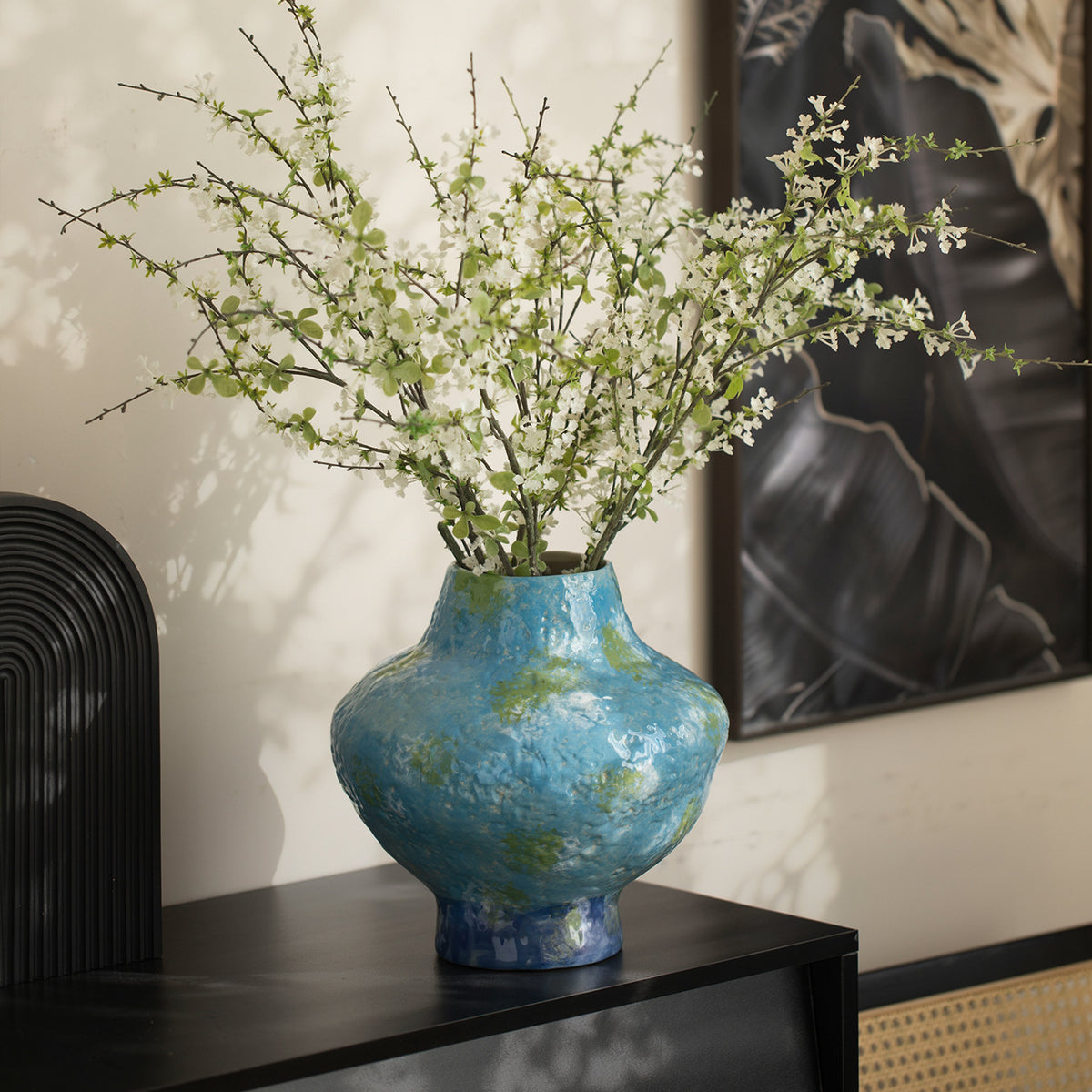 Turquoise blue mottled ceramic vase with airy white branches in modern interior