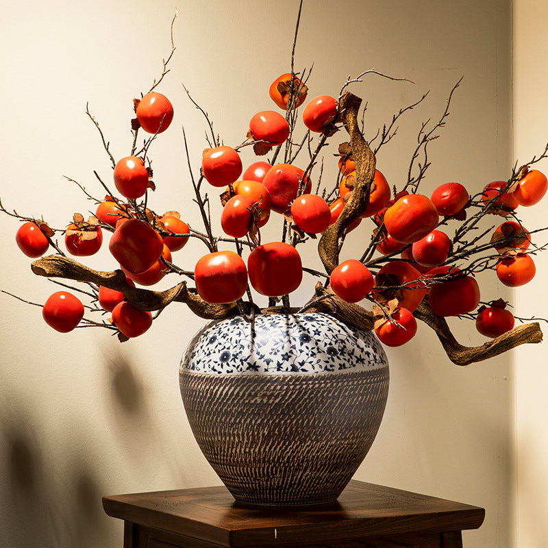Blue floral and dark carved ceramic jar with red fruit branch display