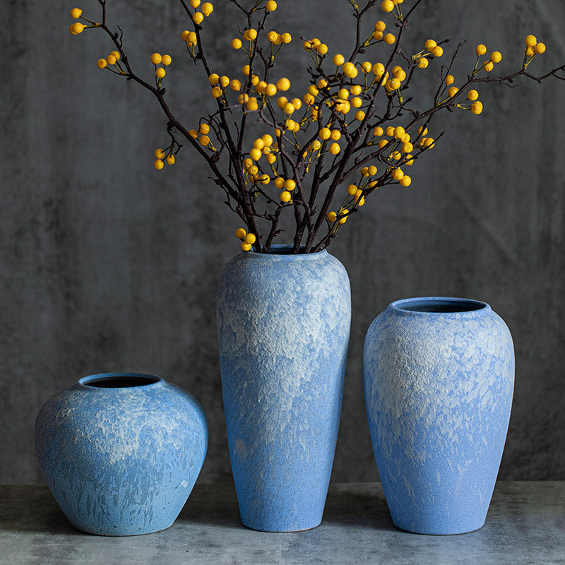 Three sky-blue ceramic vases styled with yellow berry branches