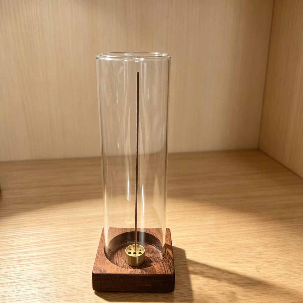 Clear cylindrical glass incense holder on square sapele wood base