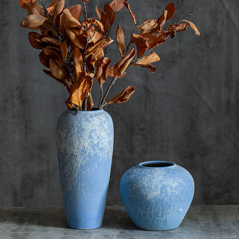 Large and small sky-blue textured ceramic vases with dried leaves