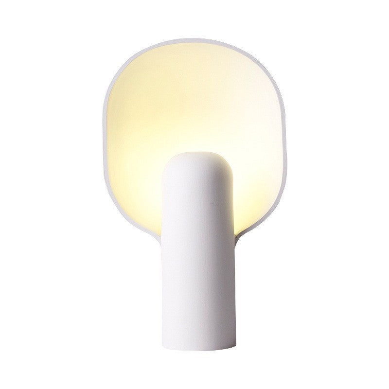 White resin table lamp glowing warmly in dark room