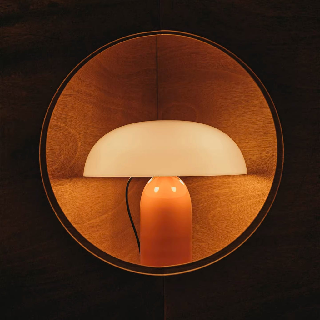 Opal and orange floating dome table lamp styled against wood wall