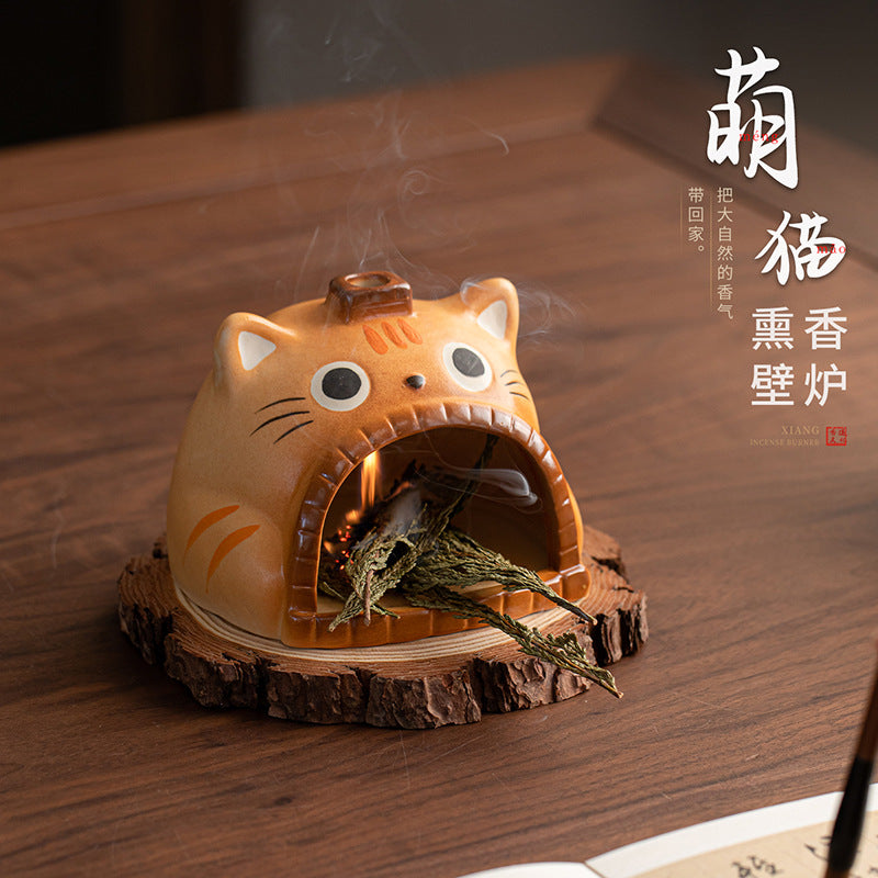 Orange cat ceramic smudge burner with herbal bundle on natural wood slice