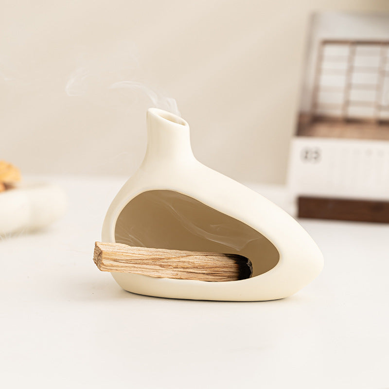 Cream ceramic Palo Santo holder with sacred wood stick in minimalist interior