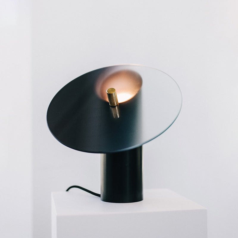 Minimalist black and clear glass disc lamp glowing warmly