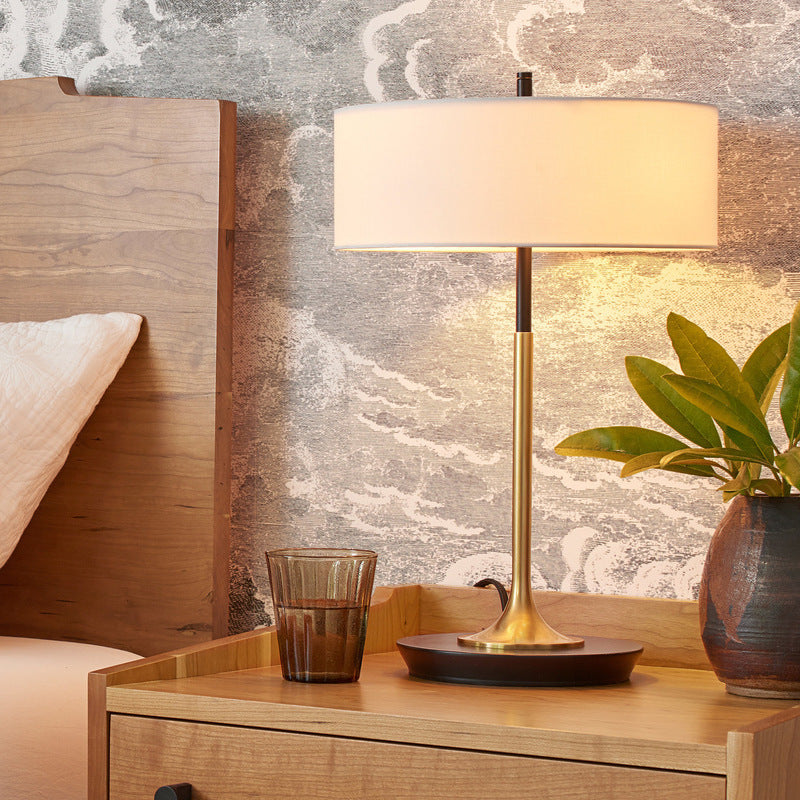 Black and brass table lamp with ivory drum shade styled on bedroom nightstand