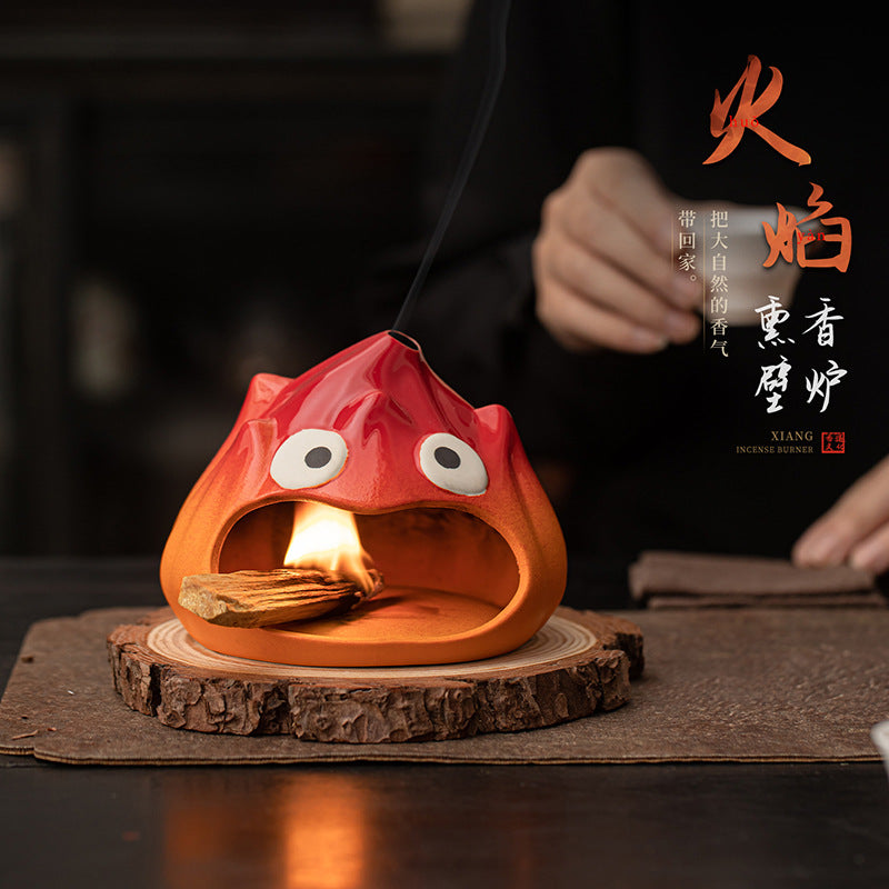 Fire red cartoon flame ceramic ritual burner glowing on natural wood coaster