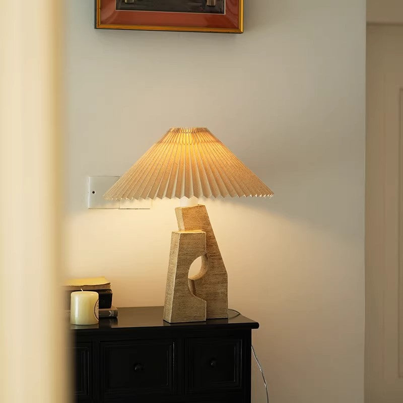 Beige sculptural resin table lamp with pleated shade in warm interior