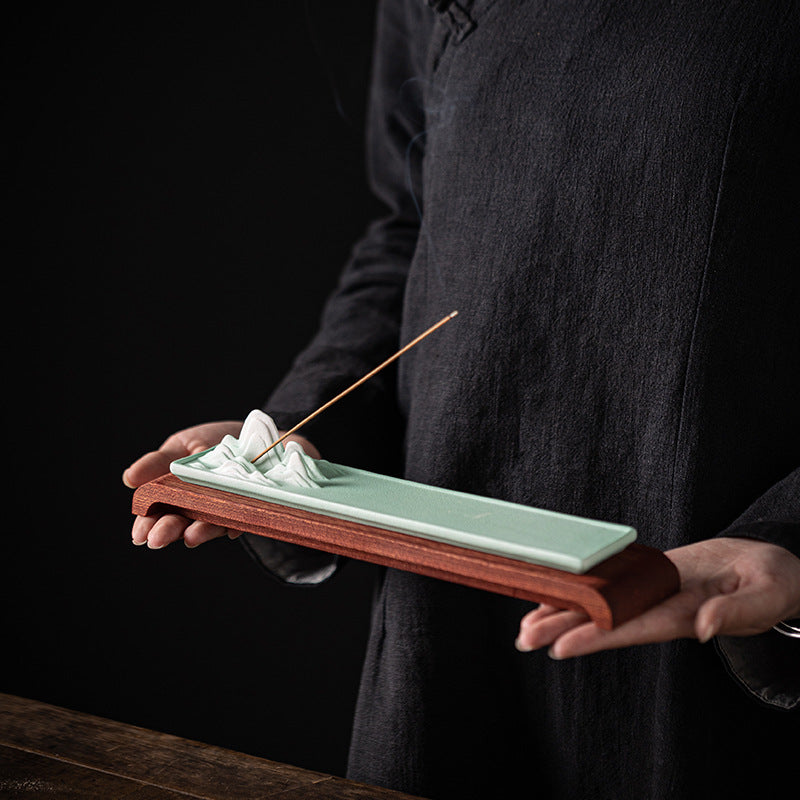 Celadon green ceramic mountain incense tray with wood base held in hands