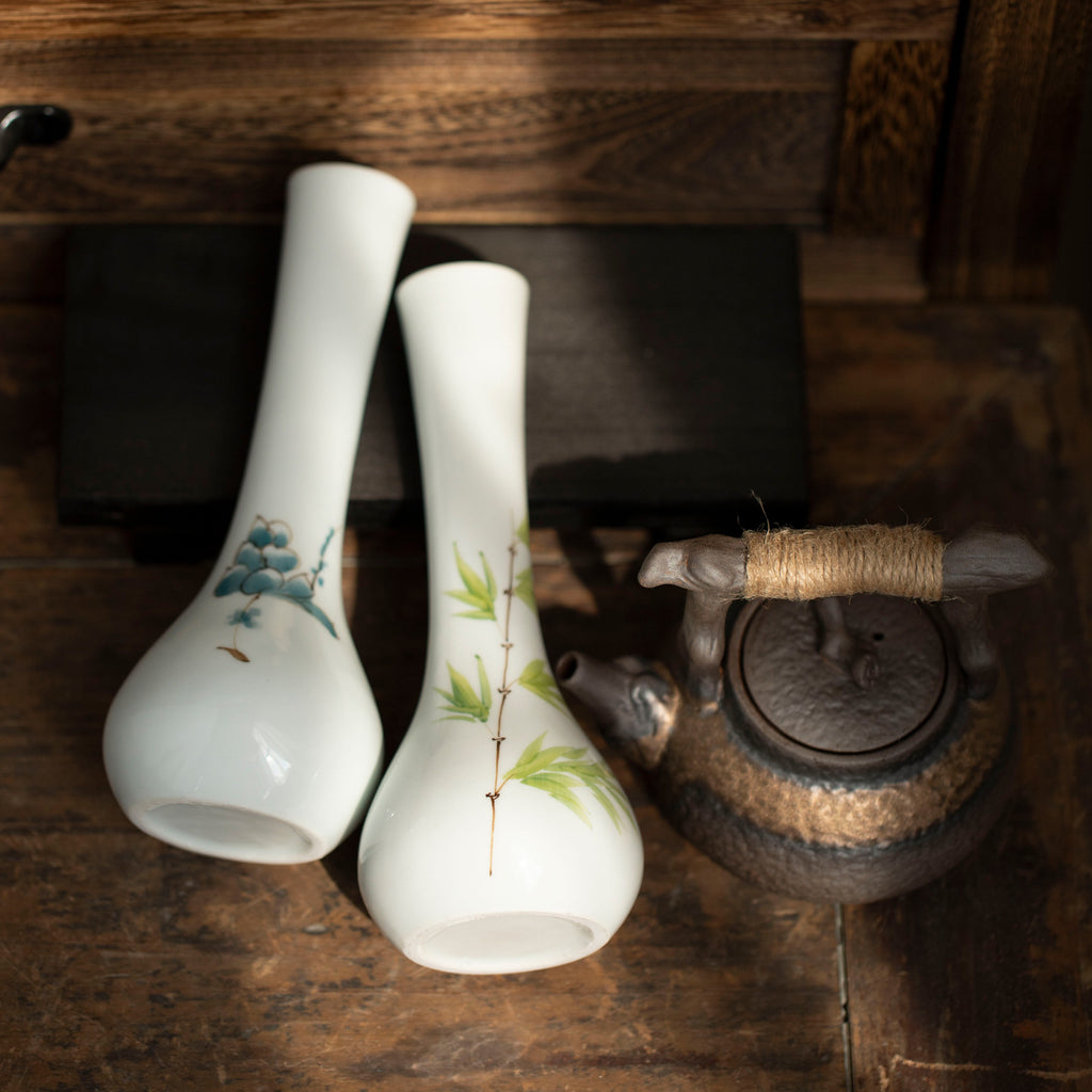 Blue floral and bamboo long-neck ceramic bud vases on rustic wood