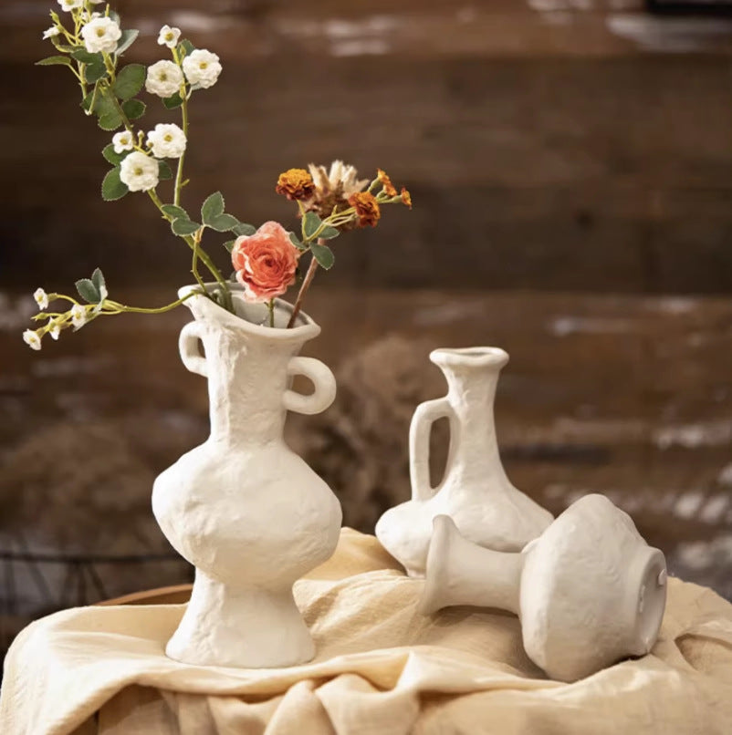White sculptural ceramic jug vases with hand-shaped texture arranged on linen