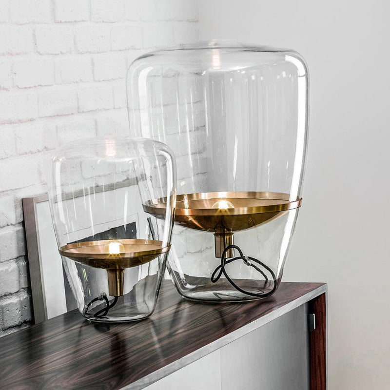 Cognac glass capsule table lamp with gold accessories on console