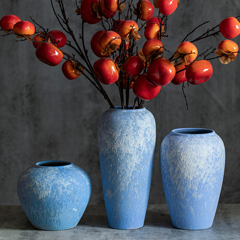 Three sky-blue textured ceramic vases with red fruit branches