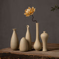 Five beige coarse-clay ceramic bud vase silhouettes styled together