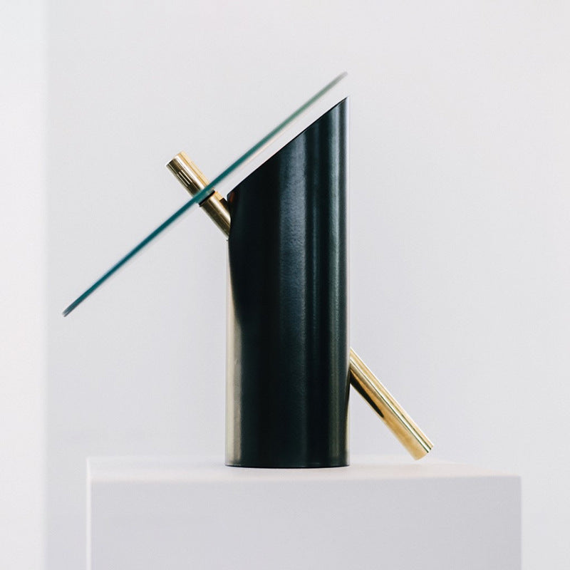 Side profile of tilted clear glass table lamp with black metal cylinder