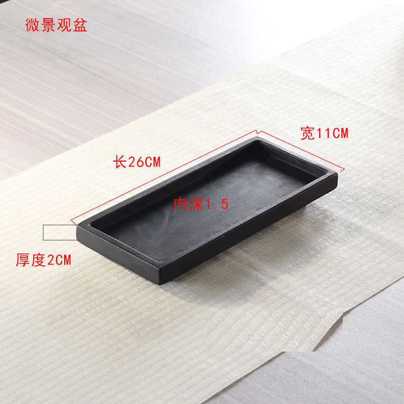 Black stone bonsai tray shown with hand for scale